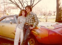 a man and woman standing next to a car