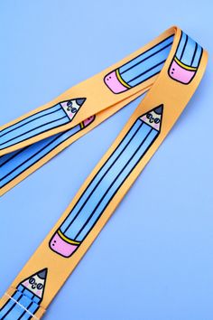 a pair of yellow pencils with blue and pink designs on them, sitting on a blue background