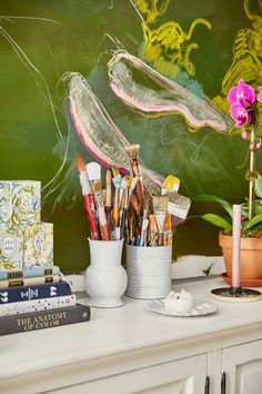 there are many paintbrushes and other art supplies on the table next to each other