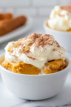 two white bowls filled with dessert on top of a table