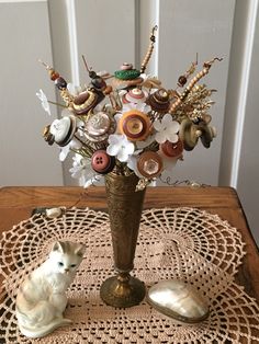 a vase filled with flowers sitting on top of a doily next to a cat figurine