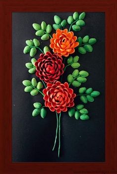 paper flowers are arranged on a black surface with green leaves in the center and bottom