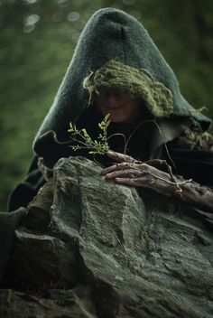 a person with a hood on holding onto a rock