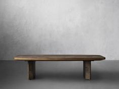 a wooden table sitting on top of a gray floor next to a white brick wall