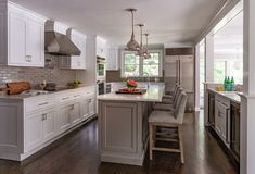 a large kitchen with white cabinets and gray counter tops, along with hardwood floorsing