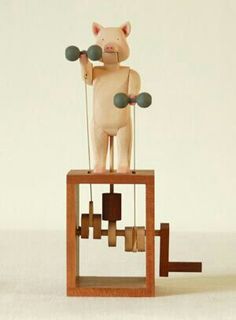 a wooden toy that is sitting on top of a stand with bells in the shape of a pig