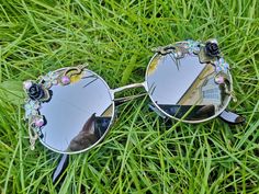 💖Women's pretty statement sunglasses. 💖These round embellished glasses are the perfect feminine touch to add to your spring / summer outfits. 💖The frames are silver metal and they have silver mirrored lenses. On either side of the glasses they have a mixture of bronze ornate details, black roses, sequin flowers and irredecent rhinestones. 💖A great accessory for holidays, music festivals or everyday wear.  💖UV protection 💖Exclusive design made by myself that you won't see anywhere else. 💖All glasses come in a black to keep them safe for delivery but please also handle with care as they are handmade. Just think of them as wearing tiny bits of wearable art.  💖Checkout the full collection of Sunglasses here :  https://www.etsy.com/uk/shop/AlexisExclusive?ref=s2-header-shopname (Colours Party Sunglasses With Gradient Round Lenses, Party Sunglasses With Gradient Round Frame, Trendy Metal Round Frame Sunglasses, Trendy Silver Round Frame Sunglasses, Chic Festival Sunglasses With Tinted Lenses, Party Sunglasses With Round Glass Frame, Trendy Metal Sunglasses For Festivals, Metal Mirrored Sunglasses For The Beach, Trendy Metal Sunglasses For Spring