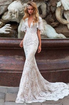 a woman standing in front of a fountain wearing a wedding dress