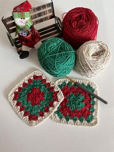 two crocheted grannys and balls of yarn sit on a table next to a chair