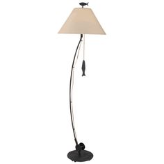 a floor lamp with a white shade on the top and a black bird sitting on it