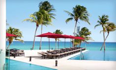 an empty swimming pool with lounge chairs and umbrellas next to the water's edge