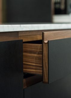 a close up view of a wooden cabinet with drawers and marble counter top in the background