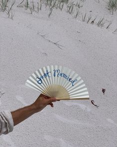 a hand holding a white fan with the words best married written on it in blue ink