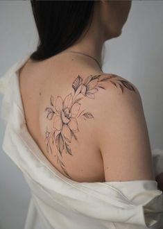 a woman with a flower tattoo on her upper arm and shoulder, wearing a white dress