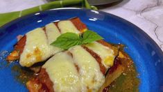 a blue plate topped with slices of pizza covered in sauce and cheese on top of green leafy garnish