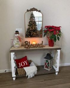 a small table with a christmas tree on top and decorations around it, along with a mirror