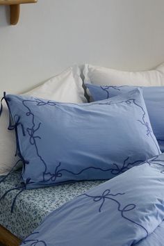 a bed with blue sheets and pillows on top of it, next to a wooden headboard