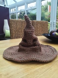 a crocheted hat sitting on top of a wooden table next to a bowl