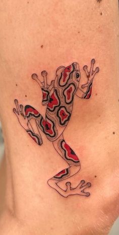 a frog tattoo on the back of a woman's lower body, with red and black designs