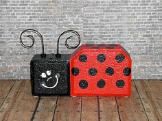 two black and red blocks with polka dots on them sitting in front of a brick wall