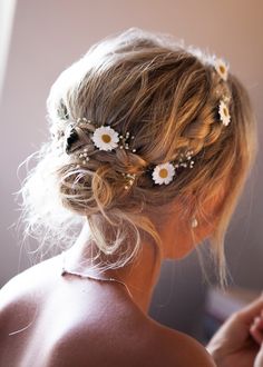 a woman with flowers in her hair is looking at something on the wall behind her