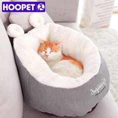 an orange and white cat sleeping in a bed on top of a couch next to a pillow