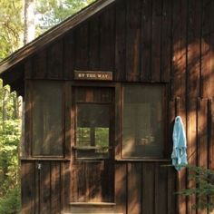 a small wooden cabin in the woods with a blue towel hanging from it's door