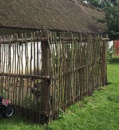 a motorcycle parked in front of a house made out of sticks