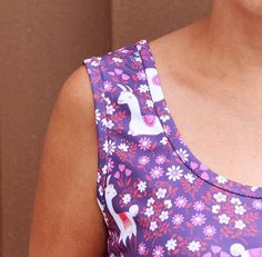 a woman wearing a purple dress with pink and white flowers on it's chest