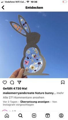 someone is holding up a paper cut out of a rabbit with flowers on its back