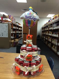 a birthday cake made out of cans on a table in a library filled with books