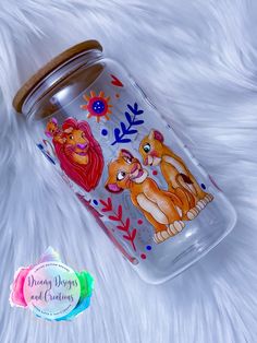 a glass jar with the lion king and princesses on it sitting on a white furnishing