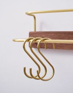 three brass hooks hang from a wooden coat rack