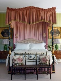 a four poster bed with pink drapes and pillows