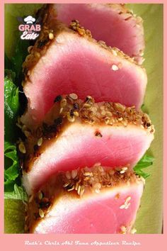 three slices of tuna with sesame seeds and garnishes on a green plate