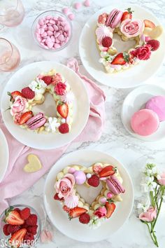 valentine's day desserts arranged on white plates with pink flowers, hearts and marshmallows