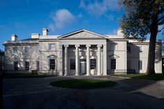 a large white building with columns and pillars on the front entrance, surrounded by trees