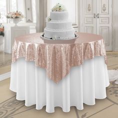 a wedding cake on top of a white table with pink and gold sequins