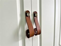 a pair of leather handles on a white door