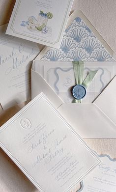 the wedding stationery is laid out on top of each other, including an envelope with a wax seal