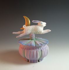 a glass figurine is sitting on top of a flower pot with a bird flying over it