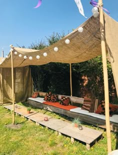 an outdoor seating area is set up in the grass with wooden benches and pillows on it