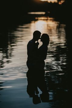 a couple kissing in the water at sunset