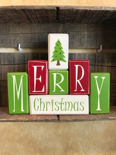 wooden blocks spelling merry christmas in front of a fireplace