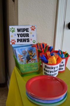 a table topped with plates and cups filled with dog paw food next to a sign that says wipe your paws