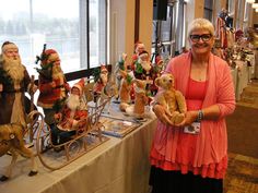 a woman standing next to a table full of christmas figurines