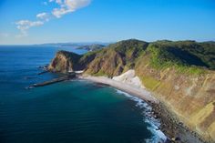 an aerial view of the ocean and coastline with mountains in the background