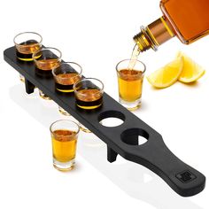 a shot glass holder with six glasses and a bottle on the side, filled with liquor