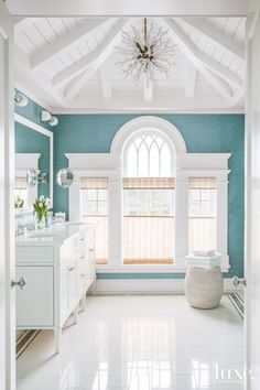 a bathroom with blue walls and white trim on the ceiling, along with a chandelier