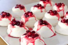 small white desserts with cranberry toppings on them sitting on a plate